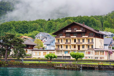 Houses by river and buildings against sky