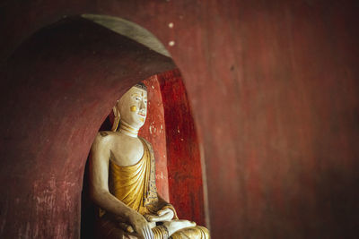 Statue of buddha against wall in building