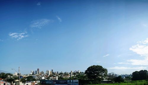 Panoramic shot of buildings and trees against blue sky