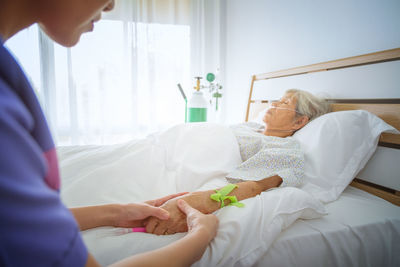 Cropped image of nurse with senior patient in hospital ward