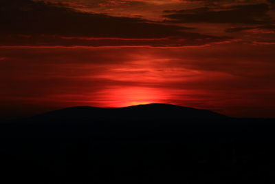 Scenic view of silhouette mountain against orange sky