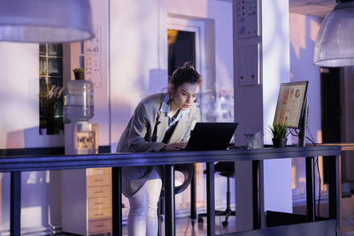 Young businesswoman using laptop while standing in cafe