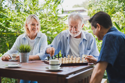 Smiling woman looking at friends playing chess on table