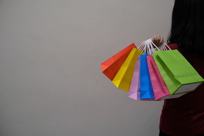 Woman holding multi colored umbrella against wall