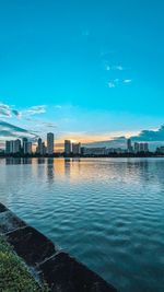 Sea by buildings against blue sky
