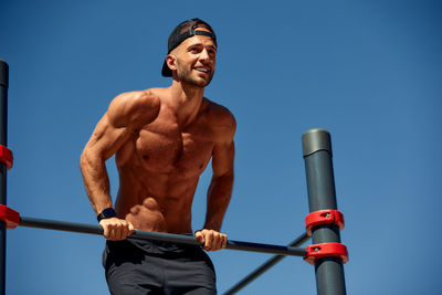 Low angle view of man exercising against clear sky