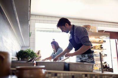 Low angle view of male and female owners working in brightly lit fish store