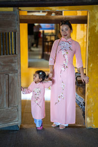 Portrait of woman standing with daughter at doorway