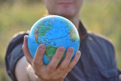 Midsection of man holding globe