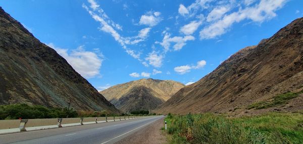 Road leading towards mountains against sky