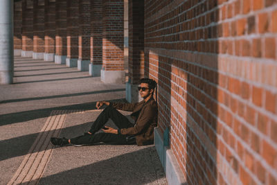 Side view of woman sitting on brick wall