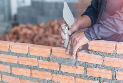 Bricklayer worker installing brick masonry on bathroom wall with trowel putty knife