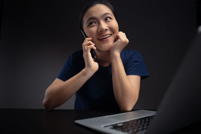 Portrait of a smiling young woman using phone