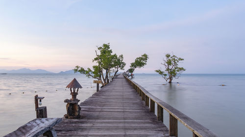 Wooden pier over sea against sky