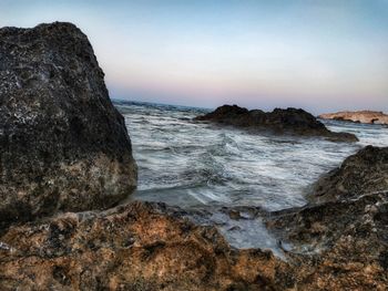 Rock formations on shore against sky