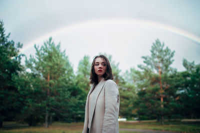 Portrait of woman standing against trees