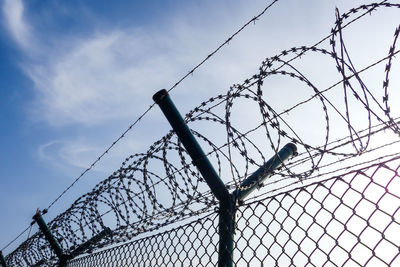 Low angle view of fence against sky during sunny day