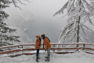 High angle view of couple kissing while standing on snow covered mountain