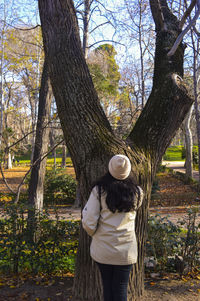 Rear view of woman standing by tree at park