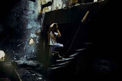 Midsection of woman sitting in abandoned building