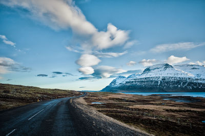 Country road against cloudy sky