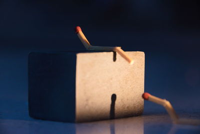 Close-up of block shape with match sticks against colored background