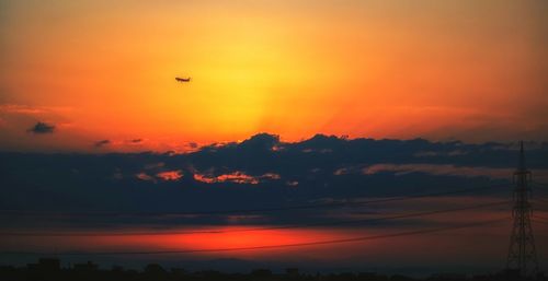 Silhouette birds flying against orange sky