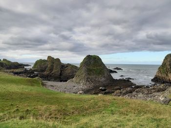 Rocks on shore by sea against sky