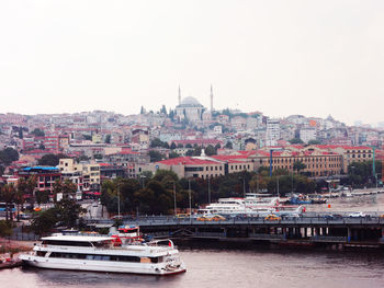 Boats moored in city by buildings against clear sky