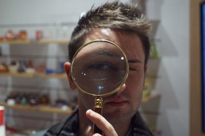 Close-up of man looking through magnifying glass at store