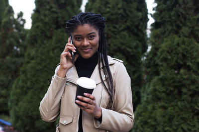 Portrait of smiling young woman using mobile phone