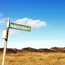 Information sign on grassy field against sky