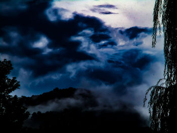 Low angle view of silhouette trees against dramatic sky