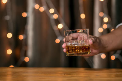Midsection of man holding wine glass on table
