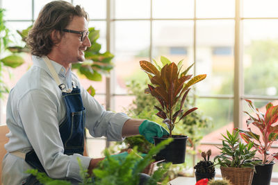 Man taking care of her potted plants at home, gardening, planting at home