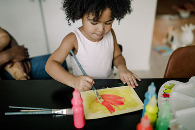 Girl painting on paper at table