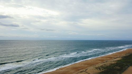 Scenic view of beach against cloudy sky