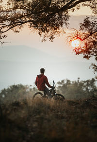 Young biker sitting on his bike at sunset during autumn