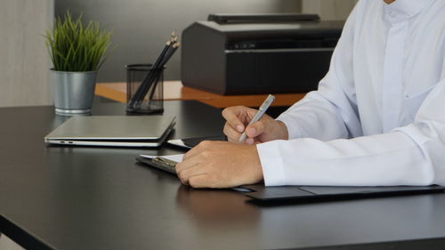 Midsection of doctor working on table