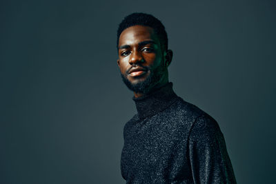 Portrait of young woman standing against black background