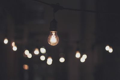 Low angle view of lit light bulb at night