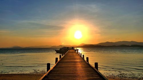 Pier over sea against sky during sunset