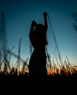 Silhouette woman standing on field against sky during sunset