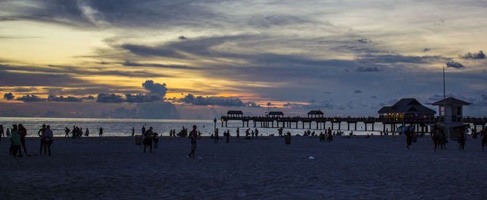 Silhouette people on beach against sky during sunset