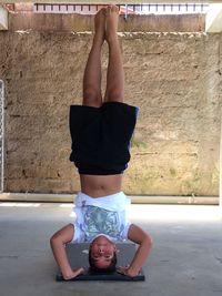 Full length of boy doing headstand against wall