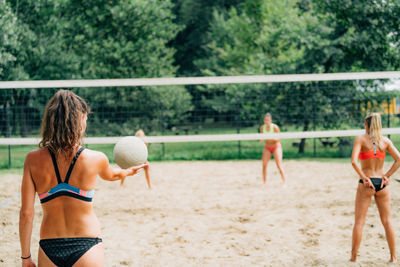 Beach volleyball, female player serving the ball