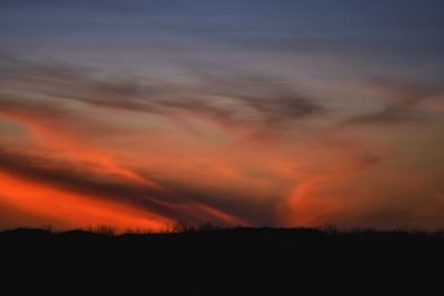 Silhouette landscape against dramatic sky during sunset