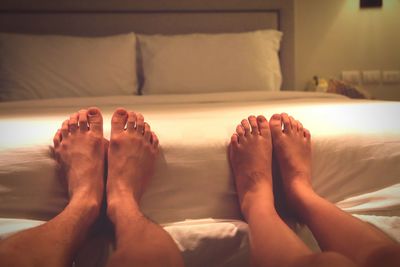 Low section of man and woman relaxing on bed