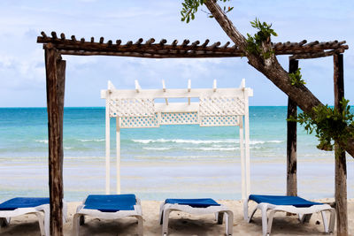 Chairs on beach against sky