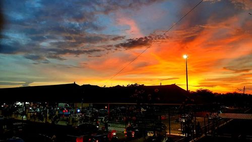 Silhouette city against dramatic sky during sunset